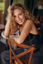 Woman Portrait. Beautiful Curly Blonde Model Resting On Chair In Cafe. Sexy Female Healthy Natural Look.