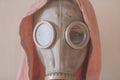 Woman portrait in a gas mask. Girl in a pink sweater and gas mask. Close-up portrait.