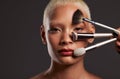Woman, portrait and makeup brushes for beauty cosmetics, skincare or facial treatment against a gray studio background