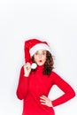 A woman portrait with a Santa hat in Christmas. She is wearing a red sweater and she is looking at the camera with a funny face.