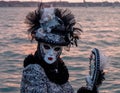 Woman poses in ornate, detailed costume, mask and hat outside San Giorgio Maggiore during Venice Carnival, Italy.