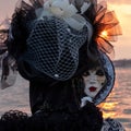 Woman poses in ornate, detailed costume, mask and hat outside San Giorgio Maggiore during Venice Carnival, Italy.