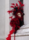 Woman poses in ornate, detailed costume, mask and hat outside San Giorgio Maggiore during Venice Carnival, Italy.