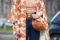 Woman poses for photographers with brown Chloe bag and golden lion head belt before Emporio Armani fashion