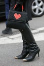 Woman poses for photographers with Les petits joueurs bag with Lego heart before Emporio Armani fashion show Royalty Free Stock Photo