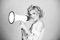 Woman posing on isolated background studio with megaphone. Screaming in megaphone. Shout girl speaks in a loudspeaker