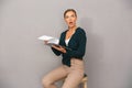 Woman posing over grey wall background holding clipboard with graphics.