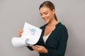 Woman posing over grey wall background holding clipboard with graphics.