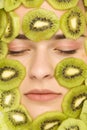 Woman posing with slices of kiwi on her face