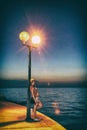 Woman posing with street lamp in Porec, analog filter