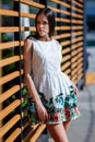 A woman is posing in a white dress on a street and on a wooden background. The lady with long dark hair is enjoying a sunny day. Royalty Free Stock Photo