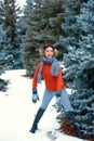 Woman is posing in winter forest, beautiful landscape with snowy fir trees. Dressed in red sweater and earmuffs Royalty Free Stock Photo