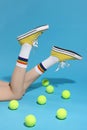 Woman posing in yellow classic old school sneakers and tennis balls on light blue background, closeup Royalty Free Stock Photo