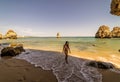 A woman tourist poses on the Praia do Camilo beach of Lagos, Portugal. Algarve region.