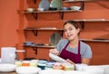 Woman potter with paintbrush glazing, painting on plate in workshop, working in pottery Royalty Free Stock Photo