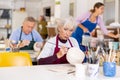 Woman potter with paintbrush, painting on plate in workshop, working in studio Royalty Free Stock Photo