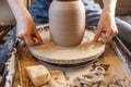 Woman potter working on a Potter`s wheel making a vase. Master pulls the jug off the circle gently holding it in hands Royalty Free Stock Photo