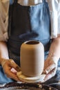 Woman potter working on a Potter`s wheel making a vase. Master pulls the jug off the circle gently holding it in hands Royalty Free Stock Photo