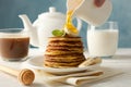 Woman pour honey on pancakes Sweet breakfast