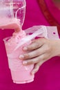 woman pour strawberry smoothie in takeaway plastic glass for sal