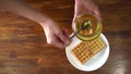 Woman pourin honey on waffles, top view