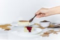 Woman pouring cacao nibs and berries sauce on slice of basque burnt cheesecake.