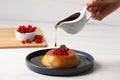 Woman pouring caramel onto delicious pudding with red currants and mint on white wooden table, closeup Royalty Free Stock Photo