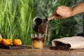 Woman pouring coffee into glass with orange juice and ice cubes at wooden table, closeup Royalty Free Stock Photo