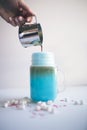 Woman is pouring coffee in stylized mason jar cup of colored blue milk. Milk shake, cocktaill, frappuccino. Unicorn coffee