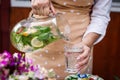 Woman pouring cold water from jug into drinking glass