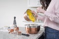 Woman pouring cookie mix into a bowl in the kitchen
