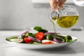 Woman pouring cooking oil onto plate with salad at white table, closeup Royalty Free Stock Photo