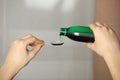 Woman pouring cough syrup into dosing spoon on blurred background, closeup Royalty Free Stock Photo