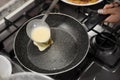 Woman pouring crepe batter onto frying pan in kitchen, closeup Royalty Free Stock Photo