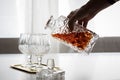 Woman pouring and drinking brandy of lead crystal bottle in cognac snifter glasses