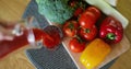 Woman pouring fresh tomato juice in glass on fresh vegetables background. Top view. Royalty Free Stock Photo