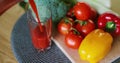 Woman pouring fresh tomato juice in glass on fresh vegetables background. Royalty Free Stock Photo