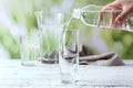 Woman pouring fresh water from bottle into glass on white wooden table Royalty Free Stock Photo