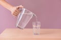 Woman pouring fresh water from jug into glass on wooden table Royalty Free Stock Photo