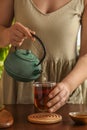 Woman pouring freshly brewed tea from teapot into cup at table, closeup. Traditional ceremony Royalty Free Stock Photo