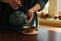 Woman pouring freshly brewed tea from teapot into cup at wooden table indoors, closeup and space for text. Traditional ceremony Royalty Free Stock Photo