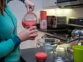 Woman pouring grapefruit margarita in wine glasses for party drinks