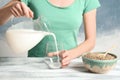 Woman pouring hemp milk into glass on table