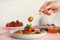 Woman pouring honey onto cereal pancakes with berries on pink wooden table, closeup Royalty Free Stock Photo