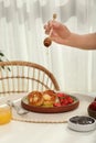 Woman pouring honey onto delicious cottage cheese pancakes at white table indoors, closeup Royalty Free Stock Photo