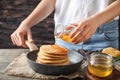 Woman pouring honey onto tasty pancakes at wooden table Royalty Free Stock Photo