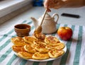 Woman pouring honey on ruddy homemade fritters. Honey dripping on tasty pancakes laid out on plate. Selective focus