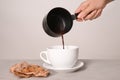 Woman pouring hot chocolate from cezve into cup on light table Royalty Free Stock Photo