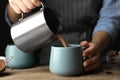 Woman pouring hot cocoa drink into cup on table, closeup Royalty Free Stock Photo