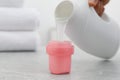 Woman pouring laundry detergent from bottle into cap at light grey marble table, closeup Royalty Free Stock Photo